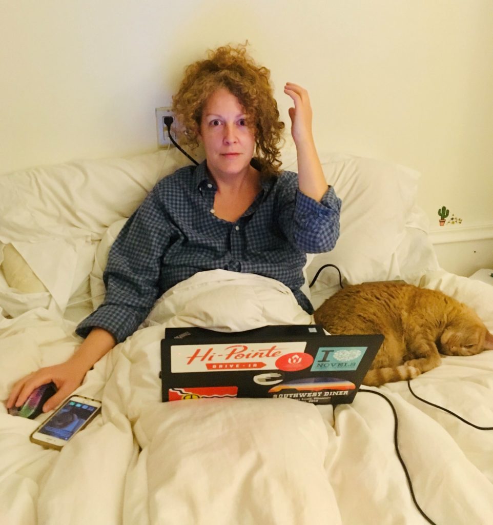 Photo of Meghan Pinson editing in bed with cat